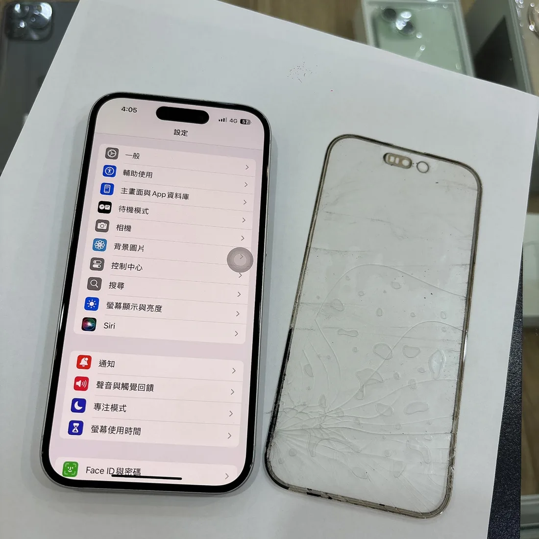 台南 iPhone 15 更換螢幕外玻璃完成,旁邊為完整分離下來的舊外玻璃
